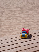 istock Little old toycar isolated on some planks with a sandy beach in background 1315555620