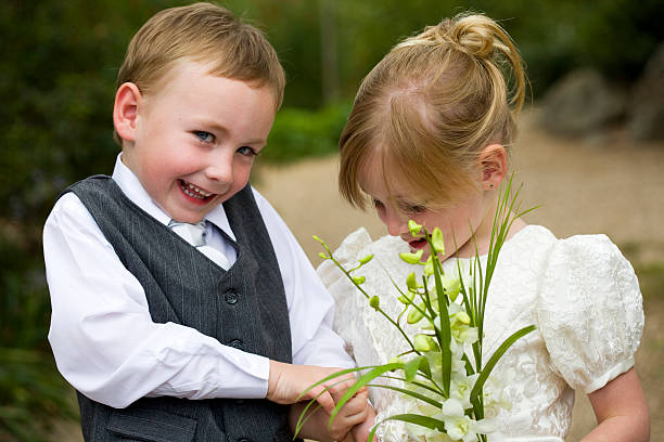 Little Page Boy Holding Hands with Flower Girl Outside stock photo