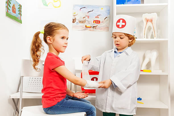 little pediatrician doctor bandaging girl's arm - flicka, armar kors bildbanksfoton och bilder