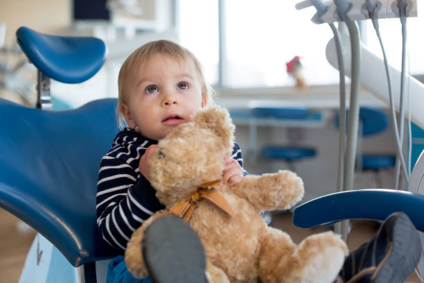 Little toddler boy with teddy bear toy at dentist's clinic for routine check-up stock photo