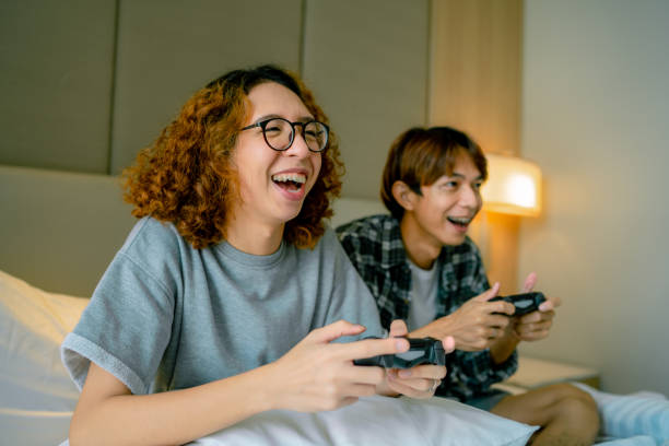 lively couple playing video game in bedroom. - enjoy repetition 個照片及圖片檔