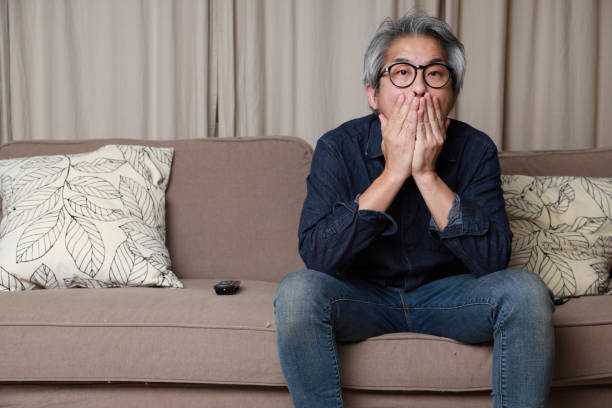 Living Room The senior Asian man sitting on the sofa in the livingroom. how do you say shut up in japanese stock pictures, royalty-free photos & images