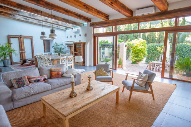 Living room view on to courtyard of Spanish farmhouse, Barcelona Elegant farmhouse living area with sofas and easy chairs and patio doors on to garden farmhouse stock pictures, royalty-free photos & images