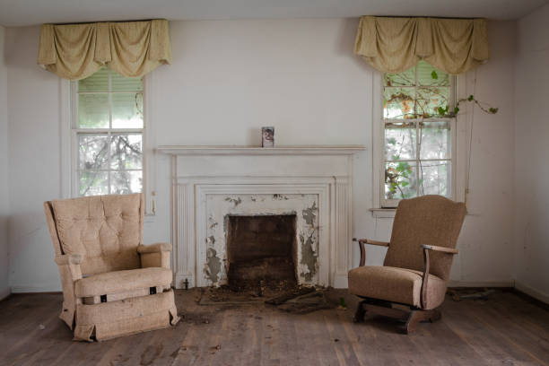 Living room with two chairs with a fireplace in an abandoned home Living room with two chairs with a fireplace in an abandoned home during the day run down stock pictures, royalty-free photos & images