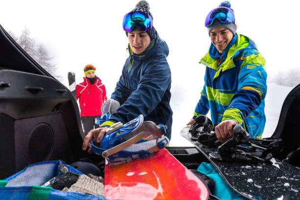 laden das auto nach einem skitag in den bergen - snowboarder in den alpen - gruppe von freunden spaß im winterurlaub - auto packen für den urlaub winter stock-fotos und bilder
