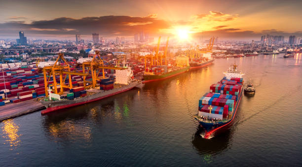 物流とコンテナー貨物船と夕日、ロジスティックの造船所のクレーン橋の勤務と貨物輸送機の輸送のインポート エクスポート輸送業界の背景 - 港湾 ストックフォトと画像