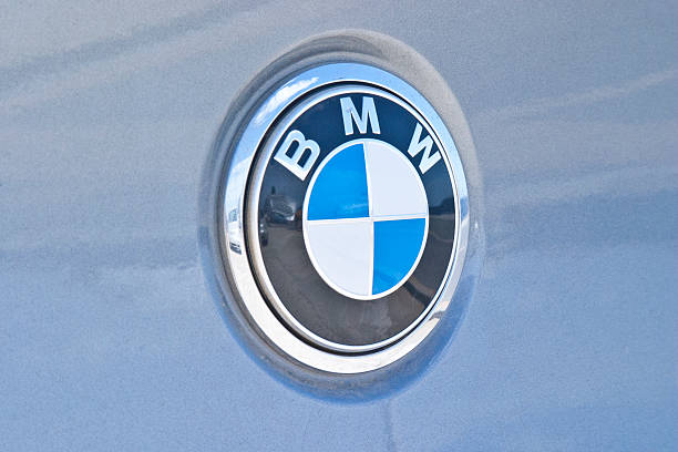 BMW Logo Mykonos, Greece - September 21, 2011: Close up of BMW (Bayerische Motoren Werke; Bavarian Motor Works) logo on a vehicle that was parked on the port of Mykonos, Greece.  One can see the reflection of a large cruise ship, the port and another car on the logo.  BMW is a German manufacturer of automobiles, motorcycles and engines.  Its logo is easily recognized world-wide by the blue and white colors in a circle, which represent the colors of Bavaria. bmw stock pictures, royalty-free photos & images