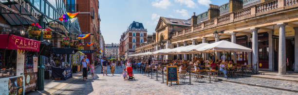 London Covent Garden people enjoying sunshine pavement cafes restaurants panorama stock photo