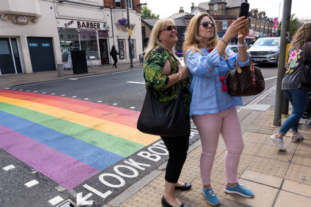 英國倫敦——2019年7月11日:兩名女性在倫敦溫布頓自拍,在街頭塗有lgbt驕傲彩虹,而不是普通街道行人過馬路,下面有暗示性文字:"兩邊看"。 - wimbledon tennis 個照片及圖片檔