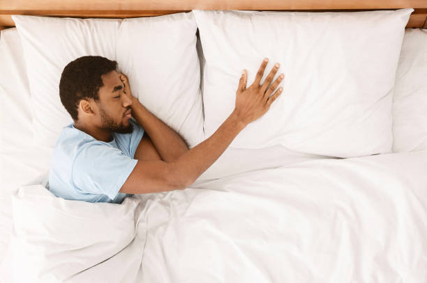 Lonely black man sleeping in bed and missing his partner Lonely black man sleeping in bed and missing his partner, touching empty pillow and sorrow, top view, free space man sleeping in bed top view stock pictures, royalty-free photos & images