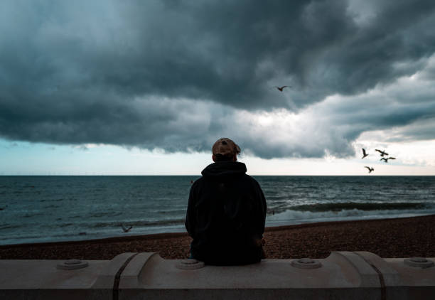 Lonely man looking at the sea and storm clouds stock photo