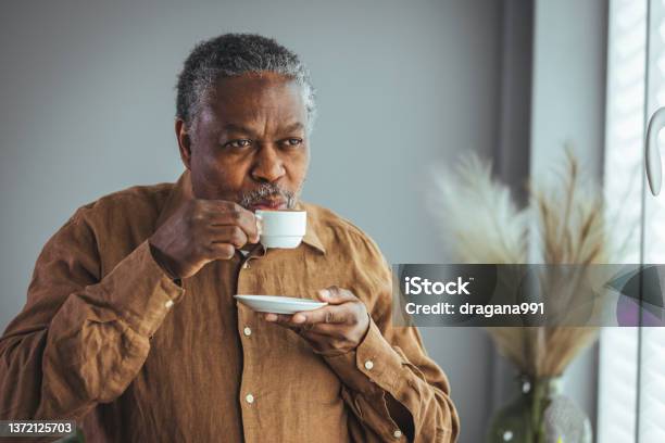 A lonely retired old African man with a white cup of coffee