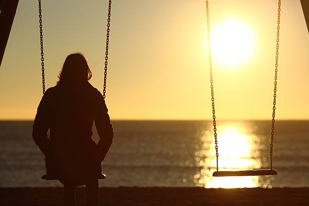 Lonely woman watching sunset alone in winter Lonely woman watching sunset alone in winter on the beach at sunset depression land feature stock pictures, royalty-free photos & images