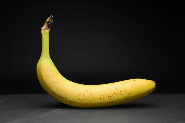 Lonely yellow banana on dark black background in studio healthy food phtography stock photo