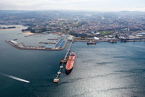Long aerial view of oil tanker in port with city behind stock photo