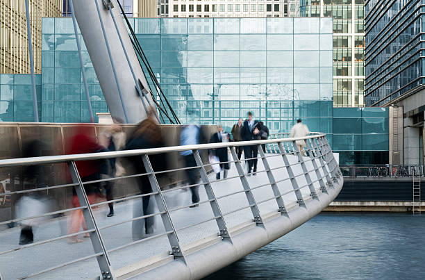 Long exposure of commuters on walkway bridge Blured City workers at Canary Wharf, London.CLIK HERE FOR MORE SIMILAR IMAGES. canary wharf stock pictures, royalty-free photos & images