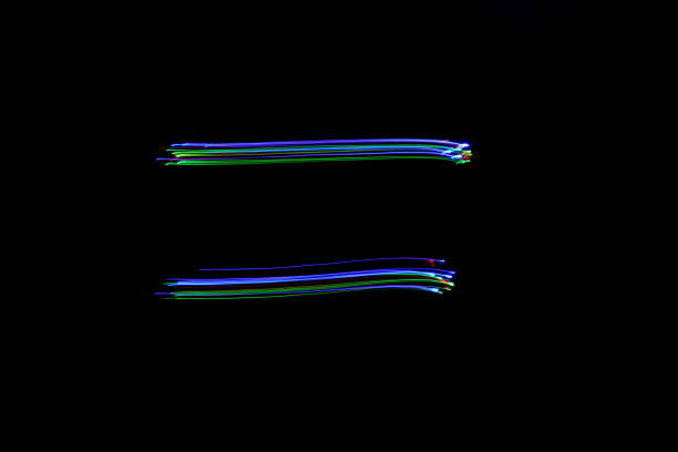 Long exposure photograph of an equals symbol in neon blue and multi colour in an abstract swirl, parallel lines pattern against a black background. Light painting photography. A light painting long exposure photo of an equals maths punctuation mark in fairy lights in a parallel lines pattern against a clean back background equal sign stock pictures, royalty-free photos & images
