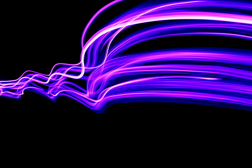 A long exposure photo of purple fairy lights in an abstract pattern against a black background
