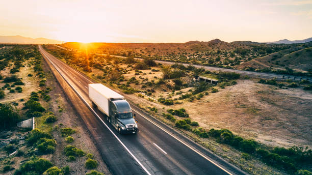 Long Haul Semi Truck On a Rural Western USA Interstate Highway Large semi truck hauling freight on the open highway in the western USA under an evening sky. trucking stock pictures, royalty-free photos & images