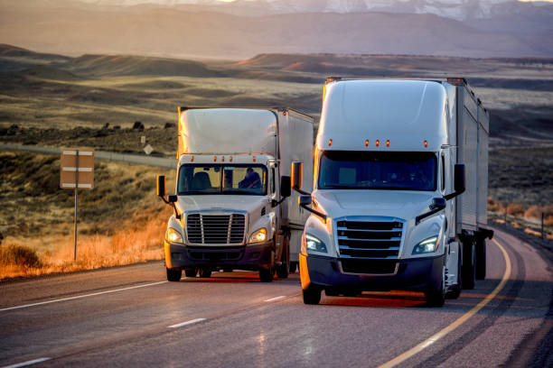 long haul semi-truck rolling down a four-lane highway at dusk - lastzug stock-fotos und bilder