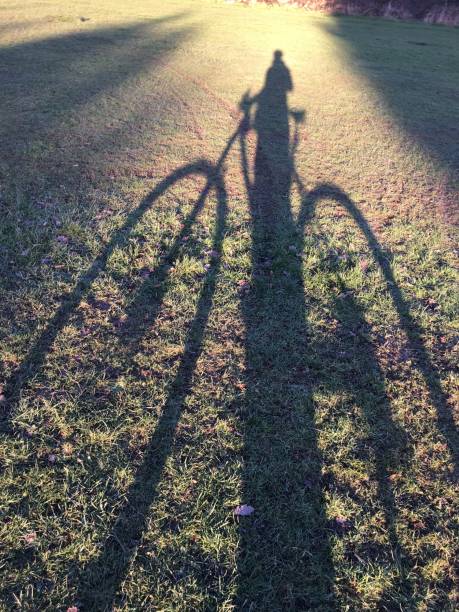 Long shadow of a man on on a bicycle stock photo
