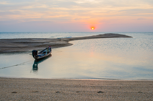 A long-tailed boat is cast anchor on the sunset beach at Koh-nokpao, Surat thani, Thailand.