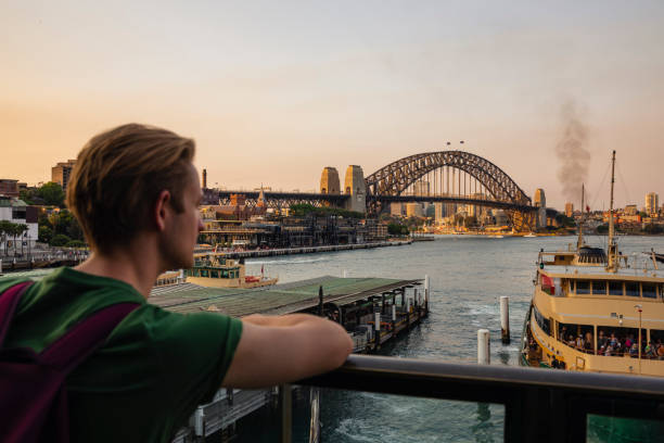 A shot of a young caucasian man in Sydney looking at the Sydney Harbour Bridge.