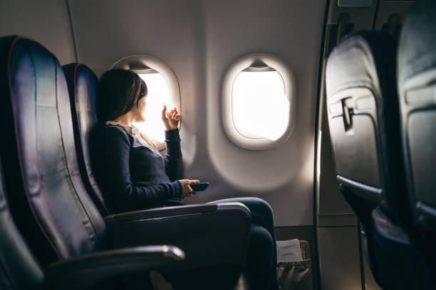 Looking through airplane window Young woman is looking through a window during airplane ride plane window seat stock pictures, royalty-free photos & images