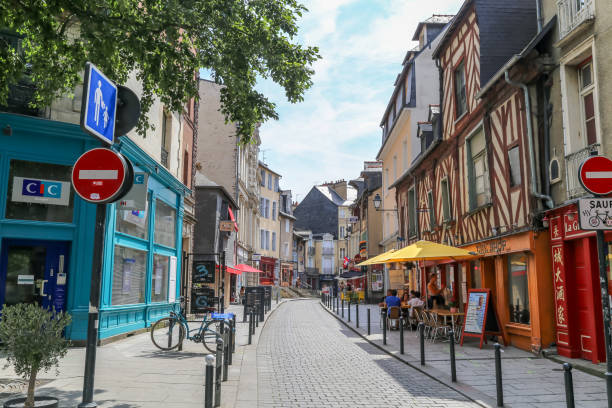 Looking up main street in Rennes, people sit in cafes and cobblestones road leads to the center of town. stock photo