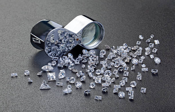 Diamantes sueltos al lado de un vidrio de lupa 10x 