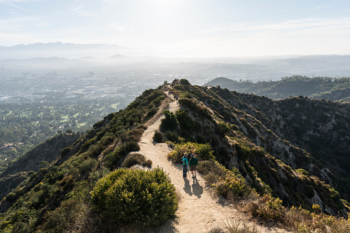 Los Angeles, California, USA - July 28, 2019:  Early morning hikers pause on Griffith Park east ridge trail above Glendale and downtown LA.