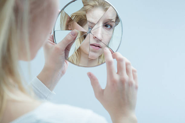 Lost herself in everyday difficulties Young woman touching her own reflection in a broken mirror bone fracture stock pictures, royalty-free photos & images