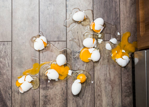 Lot of broken eggs on brown home floor. Misfortune concept. stock photo