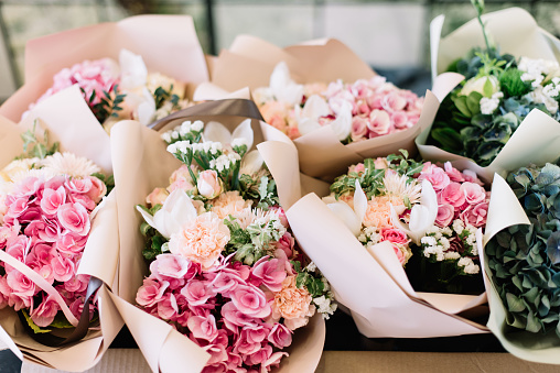 A lot of flower bouquets at the florist shop on the table made of hydrangea, roses, peonies, eustoma in pink and sea green colors