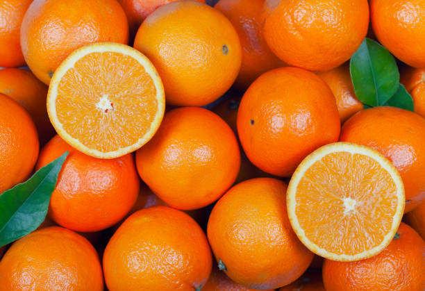 a lot of oranges with some cut in half and leaves - laranja imagens e fotografias de stock