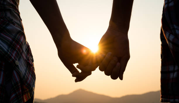 Love and Valentine day concept. A couple holding hand during sunset, a symbol of love and happy relationship. stock photo