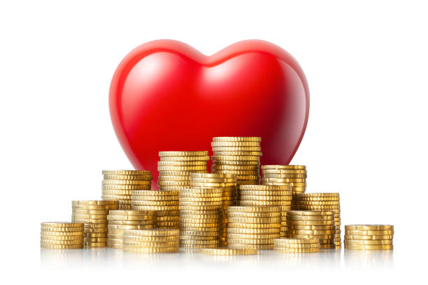 Love of money . Heart on top of a pile of coins. stock photo
