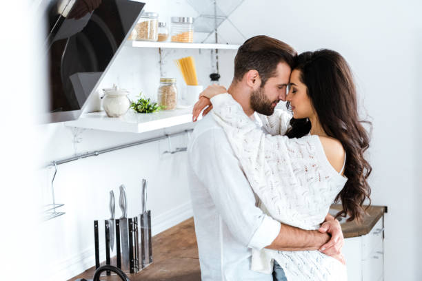 bella coppia delicatamente abbracciando con gli occhi chiusi in cucina - couple kiss foto e immagini stock