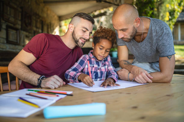 Lovely heterosexual couple doing homework with their adopted daughter stock photo