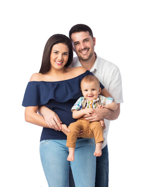 A lovely latin family with one baby boy standing, embracing and smiling at the camera.