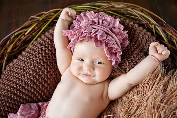Lovely little baby girl lies in a basket and stretches stock photo