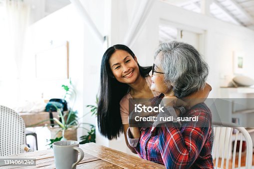 istock Loving adult daughter embracing cheerful senior mother at home 1314064240