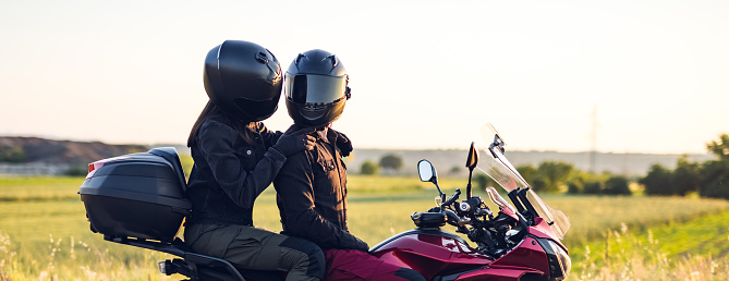 Loving couple enjoys in motorcycle ride at sunset