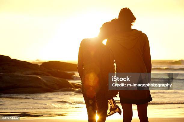 Loving couple holding hands at the beach watching the sunset