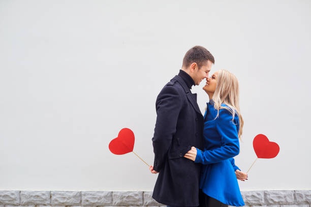 A loving couple in a coat with hearts in hands. A loving couple in a coat with hearts in hands on a gray background for text. Valentine's Day. falling in love stock pictures, royalty-free photos & images