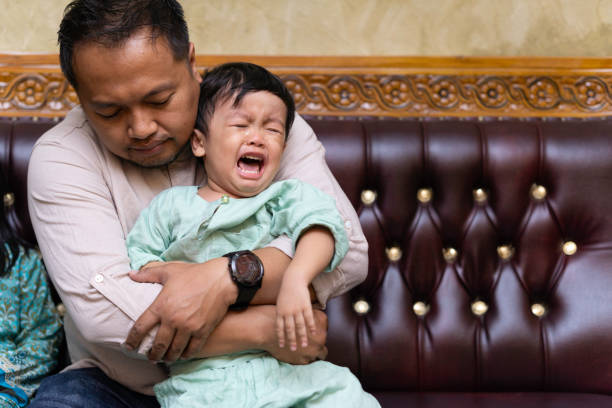 A loving father tried to comfort his cranky son at home stock photo