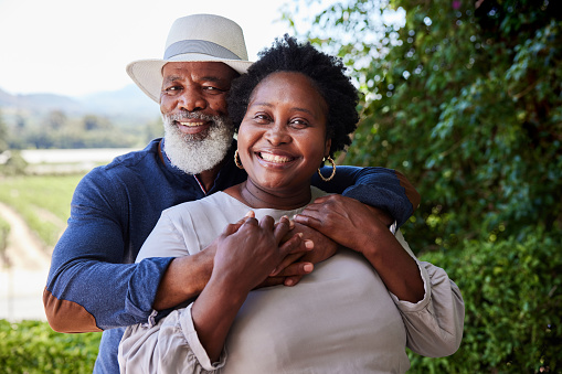 Portrait of a loving mature African couple smiling while together outside by a vineyard a sunny afternoon in the summertime