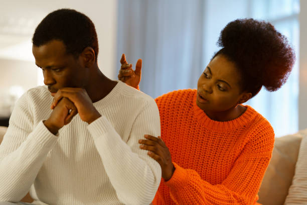 Loving wife consoling offended husband. Afro american woman supporting sad man avoid looking at her stock photo