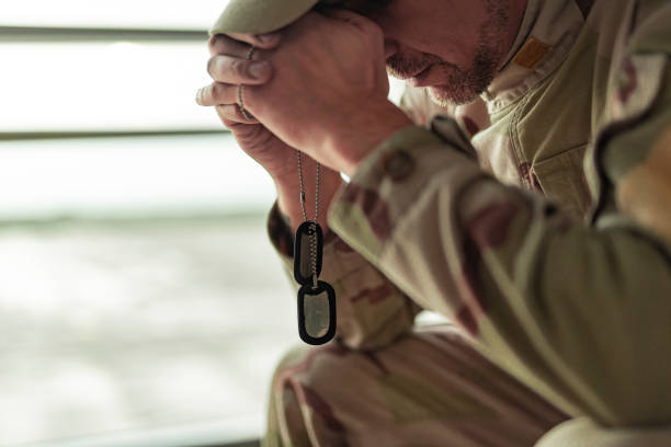 Low angle of American soldier in camouflage praying indoors stock photo