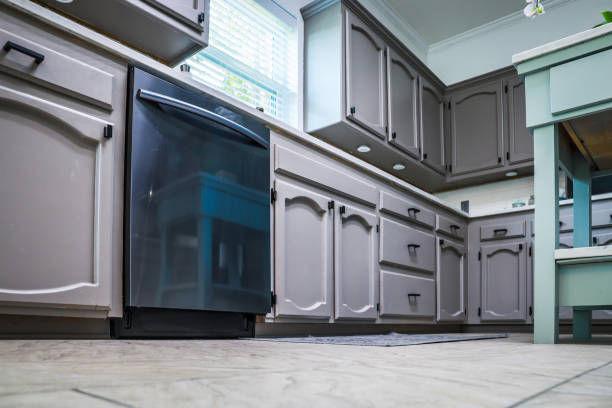 Low angle view of a renovated kitchen in an older home with painted gray cabinets, marble countertops, a small portable island and a tiled floor stock photo